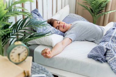 Genç bir adam yatakta uyanma ve kollarını germe