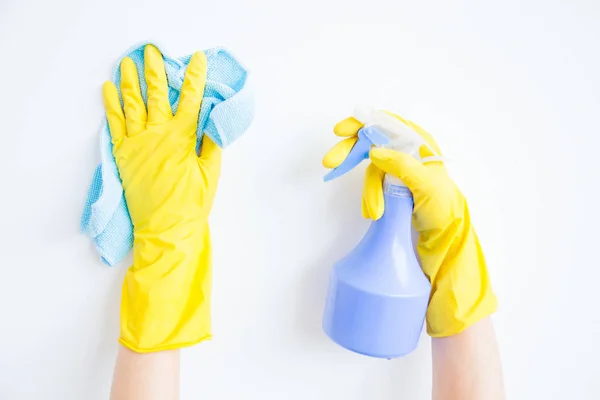 La mujer con guantes protectores sonríe y limpia el polvo con un aerosol y un plumero — Foto de Stock