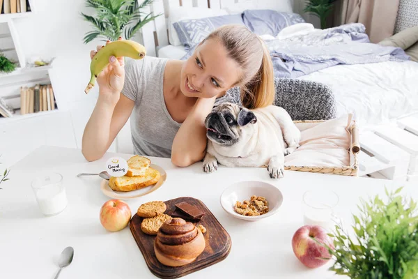 Uma jovem com o cão numa cama. Pequeno-almoço na cama — Fotografia de Stock