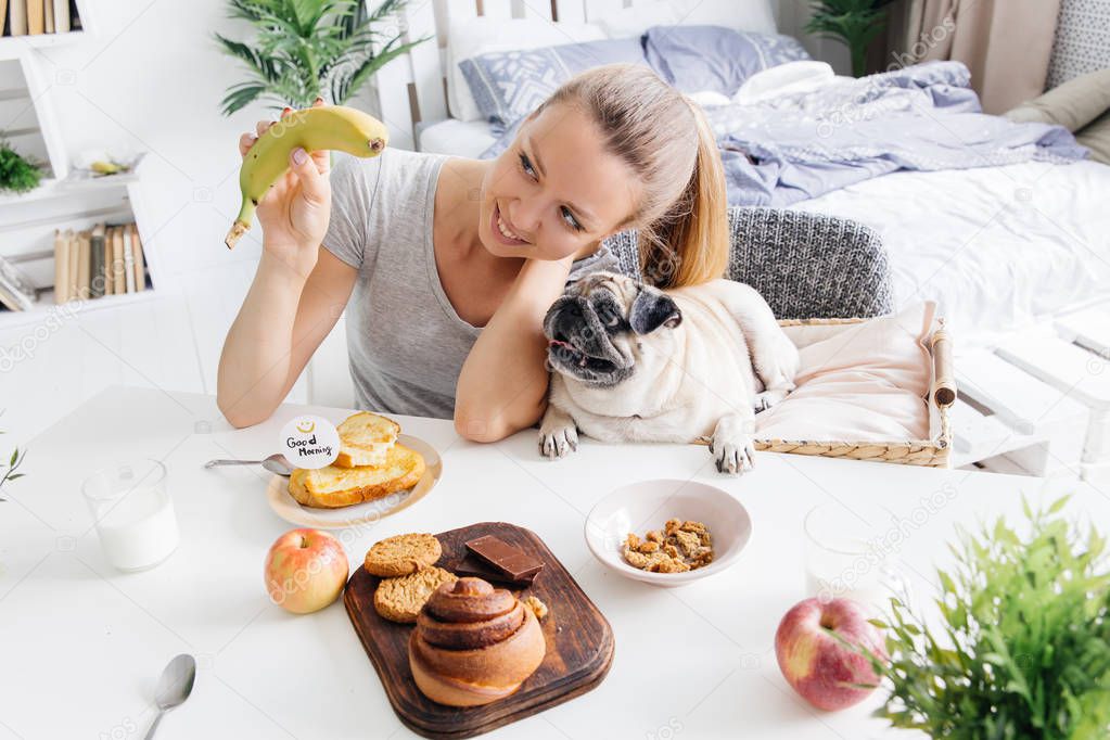 Young woman with her dog in a bed. Breakfast in bed