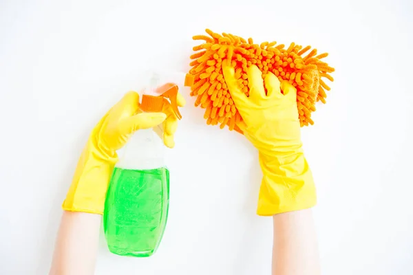 La mujer con guantes protectores sonríe y limpia el polvo con un aerosol y un plumero — Foto de Stock