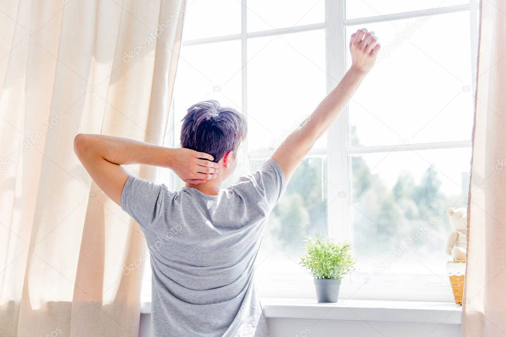 A young man waking up in bed in the morning