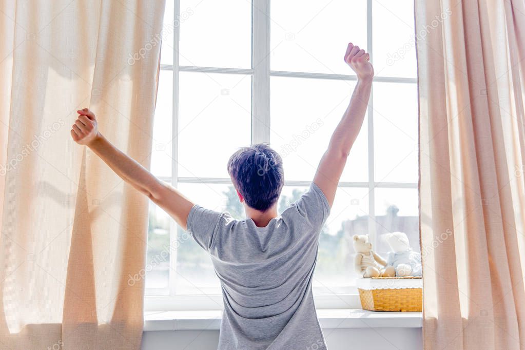 A young man waking up in bed in the morning