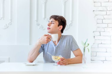 Genç adam içme kahve ve having kahvaltı