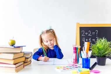 Mutlu sevimli çalışkan çocuk bir masada kapalı oturuyor