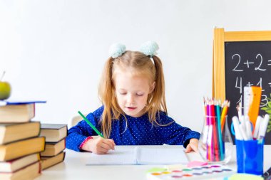 Mutlu sevimli çalışkan çocuk bir masada kapalı oturuyor