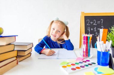 Mutlu sevimli çalışkan çocuk bir masada kapalı oturuyor