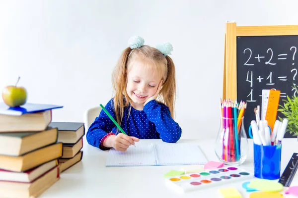 Heureux mignon enfant industrieux est assis à un bureau à l'intérieur — Photo