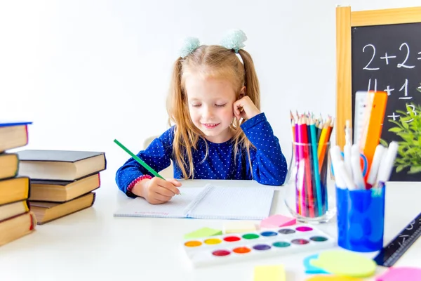 Feliz niño trabajador lindo está sentado en un escritorio en el interior — Foto de Stock