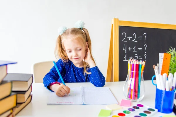 Feliz niño trabajador lindo está sentado en un escritorio en el interior — Foto de Stock