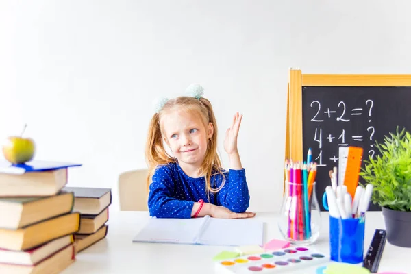 Happy cute industrious child is sitting at a desk indoors — Stock Photo, Image