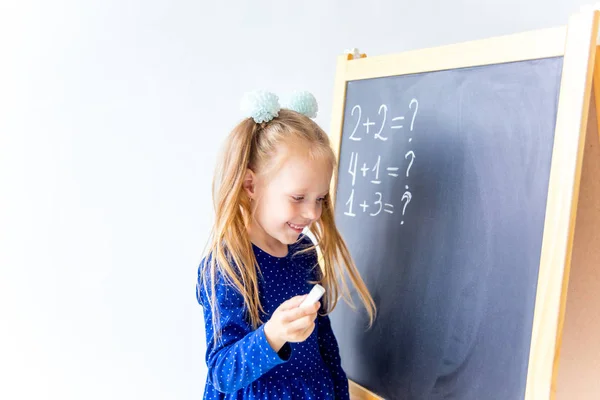 Heureux mignon enfant industrieux est assis à un bureau à l'intérieur — Photo