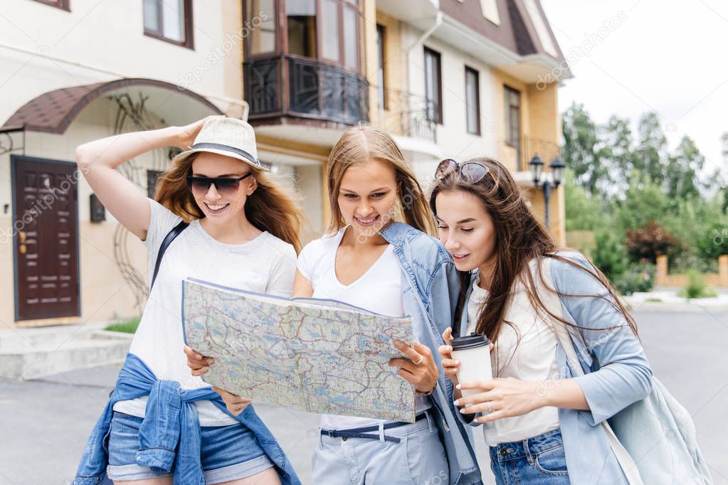 Beautiful woman traveler holding location map in hands in a city
