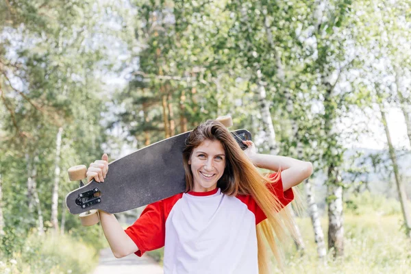 Mulher skatista bonita montando em seu longboard na cidade — Fotografia de Stock