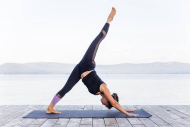 Pratik yoga bir göl üzerinde çekici genç gülümseyen kadın