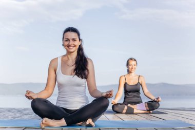 Pratik yoga bir göl kenarında genç çekici gülümseyen kadın
