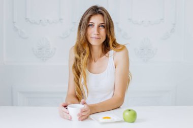 Genç ve güzel bir kadın yatakta kahvaltı yapıyor.