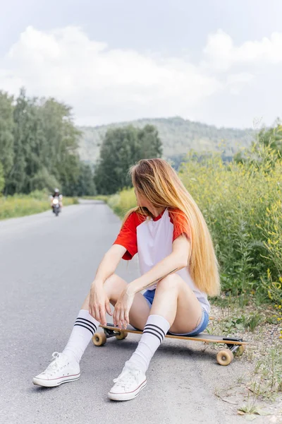 Mulher skatista bonita montando em seu longboard na cidade — Fotografia de Stock