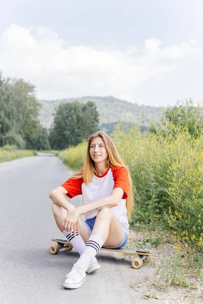 Mulher skatista bonita montando em seu longboard na cidade — Fotografia de Stock