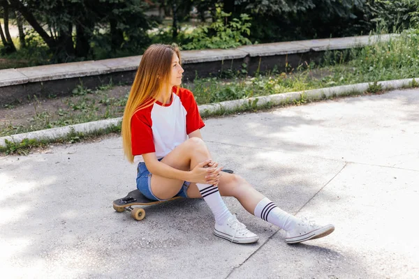 Mulher skatista bonita montando em seu longboard na cidade — Fotografia de Stock