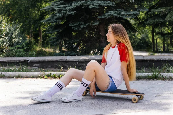 Mulher skatista bonita montando em seu longboard na cidade — Fotografia de Stock