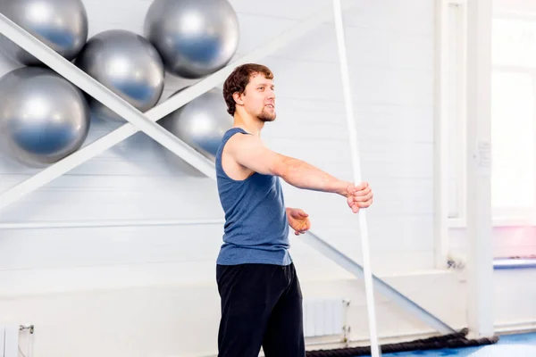 Young muscular man doing crossfit exercises in a gym