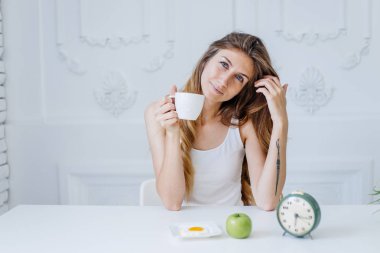 Genç ve güzel bir kadın yatakta kahvaltı yapıyor.