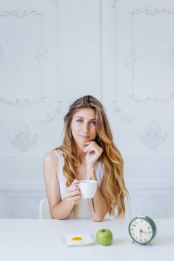 Genç ve güzel bir kadın yatakta kahvaltı yapıyor.