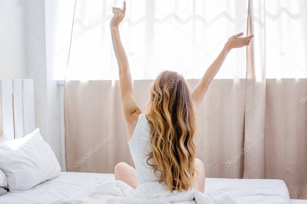 a portrait of a woman stretching in bed after wake up