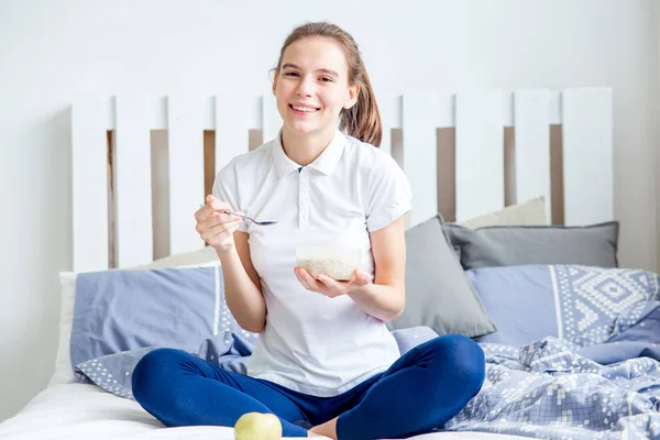 Leende friska flicka äter cornflakes spannmål och äter frukost — Stockfoto