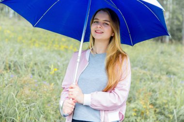 yağmur altında mavi şemsiyesi altında duran genç kadın