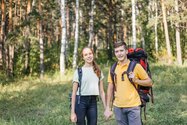 Casal de turistas com mochilas caminhadas em uma floresta — Fotografia de Stock