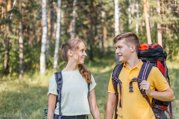 Couple of tourists with backpacks hiking in a forest — Stock Photo, Image