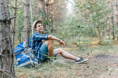 Genç erkek uzun yürüyüşe çıkan kimse oturarak ve ormanda dinlenme