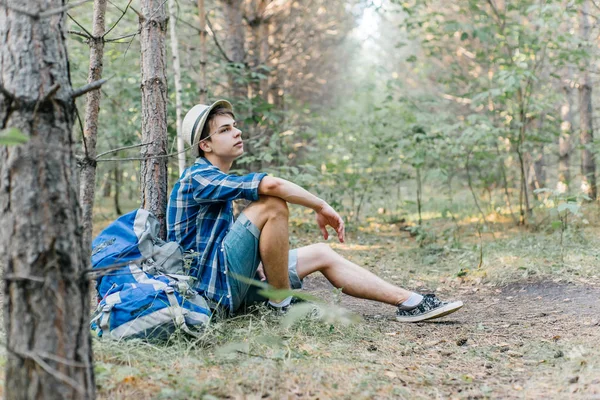 Genç erkek uzun yürüyüşe çıkan kimse oturarak ve ormanda dinlenme — Stok fotoğraf