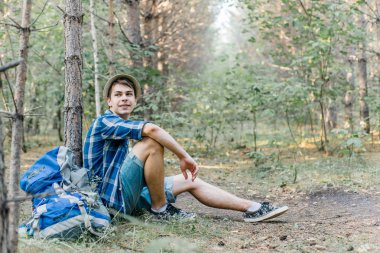 Genç erkek uzun yürüyüşe çıkan kimse oturarak ve ormanda dinlenme