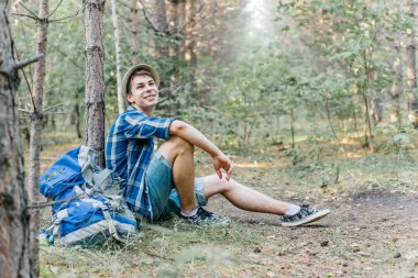 Genç erkek uzun yürüyüşe çıkan kimse oturarak ve ormanda dinlenme