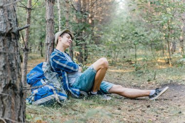 Genç erkek uzun yürüyüşe çıkan kimse oturarak ve ormanda dinlenme