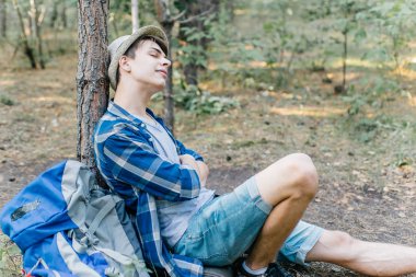 Genç erkek uzun yürüyüşe çıkan kimse oturarak ve ormanda dinlenme
