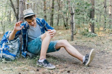 Genç erkek uzun yürüyüşe çıkan kimse oturarak ve ormanda dinlenme
