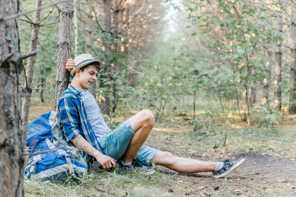 Genç erkek uzun yürüyüşe çıkan kimse oturarak ve ormanda dinlenme — Stok fotoğraf