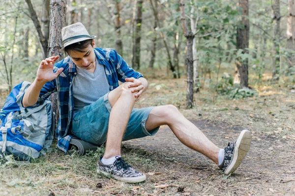 Genç erkek uzun yürüyüşe çıkan kimse oturarak ve ormanda dinlenme