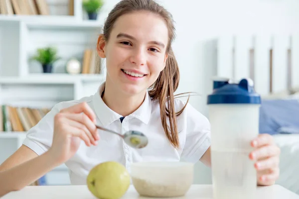 Sorrindo menina saudável comer flocos de milho cereais e tomar café da manhã — Fotografia de Stock