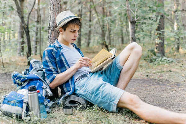 Jovem caminhante do sexo masculino está sentado e descansando na floresta — Fotografia de Stock