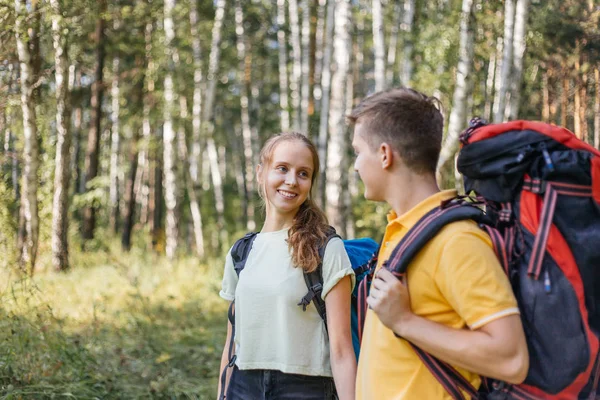 Casal de turistas com mochilas caminhadas em uma floresta — Fotografia de Stock