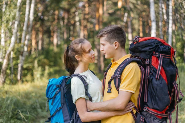 Couple of tourists with backpacks hiking in a forest — Stock Photo, Image