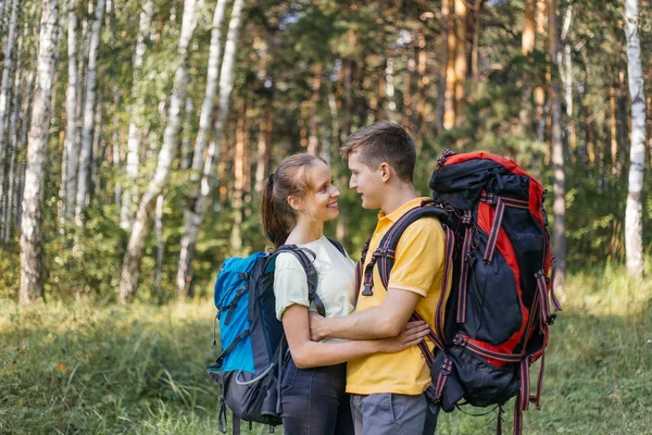 Couple of tourists with backpacks hiking in a forest — Stock Photo, Image