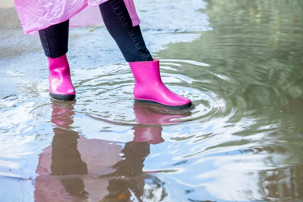 woman in rubber boots and a raincoat walking in the rain