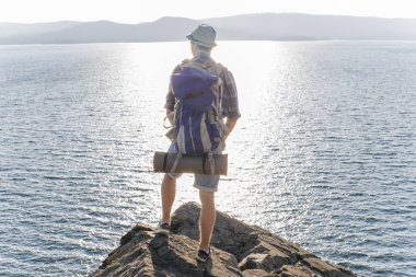 Uzun yürüyüşe çıkan kimse sırt çantası ile bir dağın tepesinde olduğunu