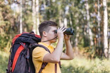 Yürüyüşçü adam dürbünle bakıyor. Manzaranın tadını çıkarıyor.